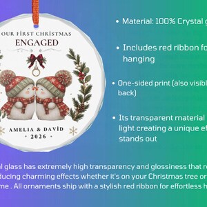 May include: A round crystal glass ornament featuring a printed illustration of two snowmen wearing red hats and scarves, with the text "OUR FIRST CHRISTMAS ENGAGED", "AMELIA & DAVID", and "2026". A red ribbon is attached to the top for hanging purposes.