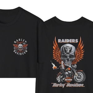 K&ouml;nnte beinhalten: Ein schwarzes T-Shirt mit einem kleinen Harley-Davidson-Logo auf der Brust. Die R&uuml;ckseite zeigt eine gro&szlig;e Grafik eines Sch&auml;dels mit Raiders-Helm und orangefarbenen Fl&uuml;geln, eine Person auf einem Motorrad sowie den Text Raiders und Harley-Davidson.