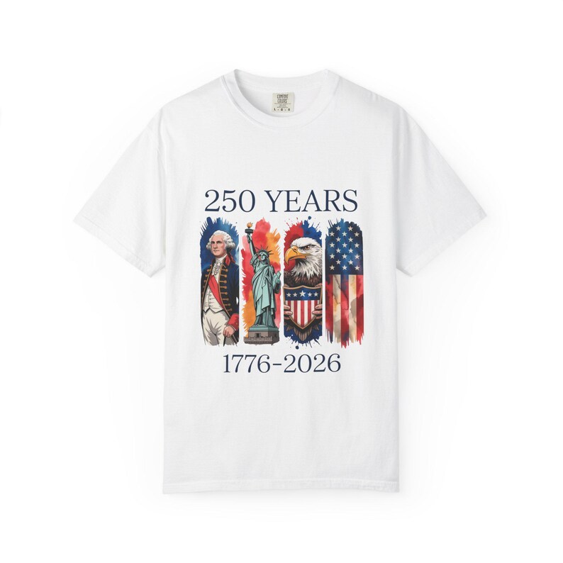 May include: White t-shirt featuring a patriotic design. The shirt displays the text "250 YEARS 1776-2026" above images of George Washington, the Statue of Liberty, an eagle, and the American flag. The design incorporates red, white, and blue.