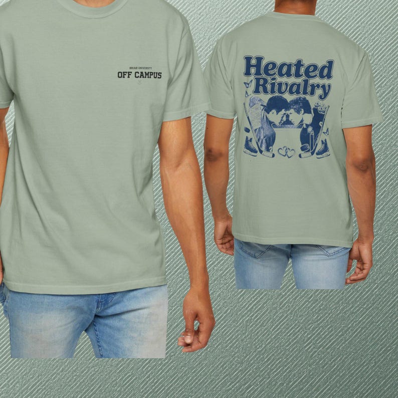 Peut inclure: Un t-shirt &agrave; manches courtes vert sauge avec un petit logo noir sur la poitrine indiquant OFF CAMPUS. Le dos du t-shirt pr&eacute;sente un grand motif bleu fonc&eacute; avec le texte Heated Rivalry, illustrant deux joueurs de hockey sur glace.