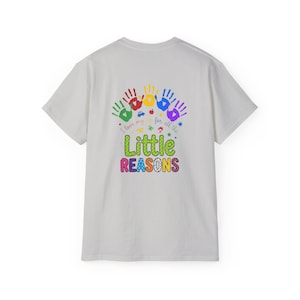 May include: A light gray t-shirt featuring a colorful graphic on the back. The design includes five handprints in green, red, yellow, blue, and purple, with the text I love my job for all the Little REASONS and small icons of a car and apple.