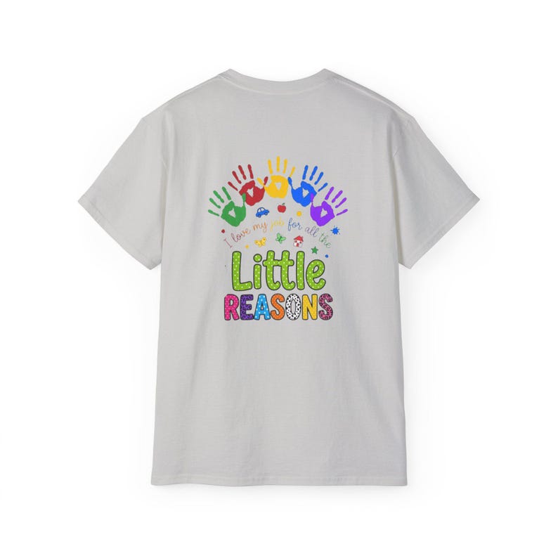 May include: A light gray t-shirt featuring a colorful graphic on the back. The design includes five handprints in green, red, yellow, blue, and purple, with the text I love my job for all the Little REASONS and small icons of a car and apple.