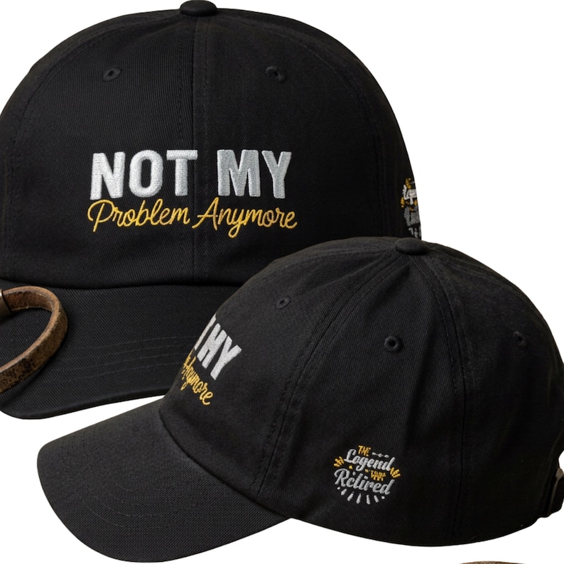 Op de afbeelding: Een zwarte honkbalpet met de wit en geel geborduurde tekst "NOT MY Problem Anymore" op de voorkant. De zijkant van de pet toont een cirkelvormig geborduurd embleem met de tekst "THE Legend HAS Retired" in het wit en geel.