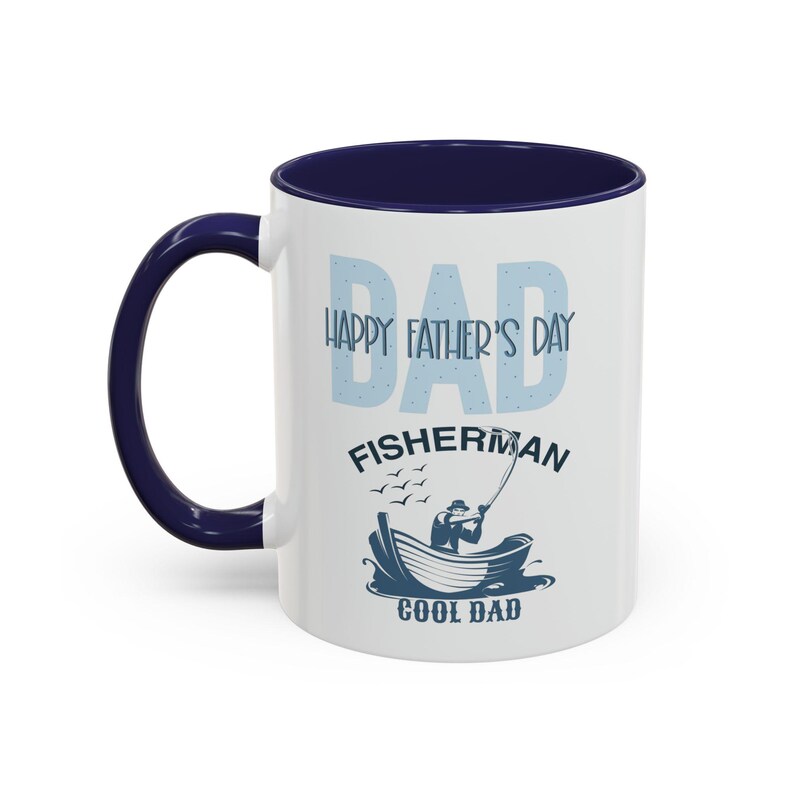 May include: White ceramic mug with a navy blue interior and handle. The mug features the text "DAD HAPPY FATHER'S DAY FISHERMAN COOL DAD" in light blue, along with a graphic of a fisherman in a boat.