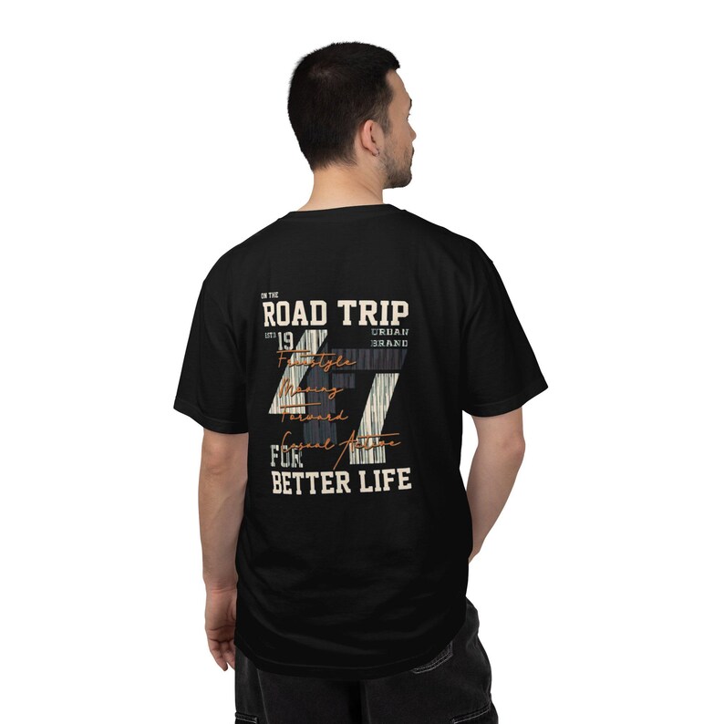 May include: A black short-sleeve t-shirt featuring a graphic on the back with the text ON THE ROAD TRIP EST 19 URBAN BRAND FOR BETTER LIFE. The design includes a large number 47 with a striped pattern and the words Freestyle Moving Forward Casual Active.