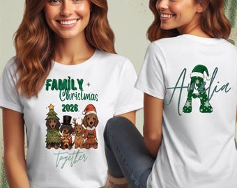 Op de afbeelding: Een wit t-shirt met een afbeelding van vier teckels in kerstkleding met de tekst Family Christmas 2026 together op de voorkant, en een grote groene letter A met een kerstmuts en de naam Amelia op de achterkant.