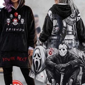 May include: A black hooded blanket sweatshirt featuring a graphic of horror movie characters and the text FRIENDS and YOU'RE NEXT on the front, with a large back print of various horror icons including a masked figure and a doll.