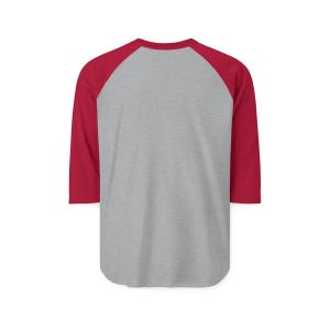 May include: A baseball-style shirt featuring a heather gray torso and solid red three-quarter length raglan sleeves. The garment has a rounded neckline and a curved hemline, showcasing a classic two-tone design with a plain, unadorned back view.