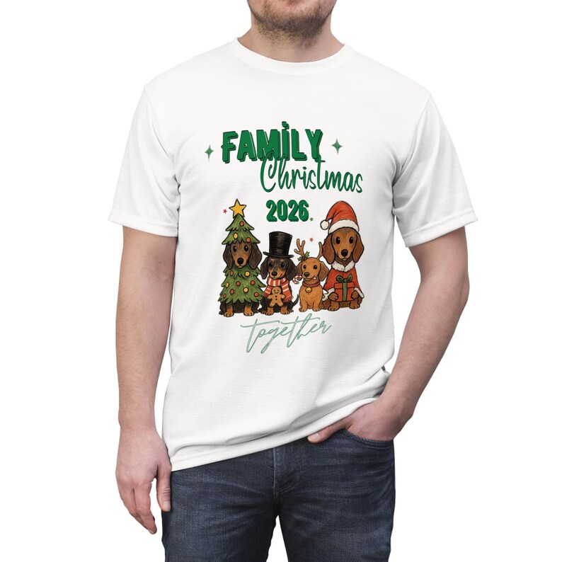 Puede incluir: Una camiseta blanca de manga corta con un gr&aacute;fico de cuatro perros salchicha vestidos para las fiestas. El texto dice "FAMILY Christmas 2026 together". Un perro est&aacute; dentro de un &aacute;rbol, otro lleva un sombrero de copa, otro tiene astas de reno y otro un gorro.