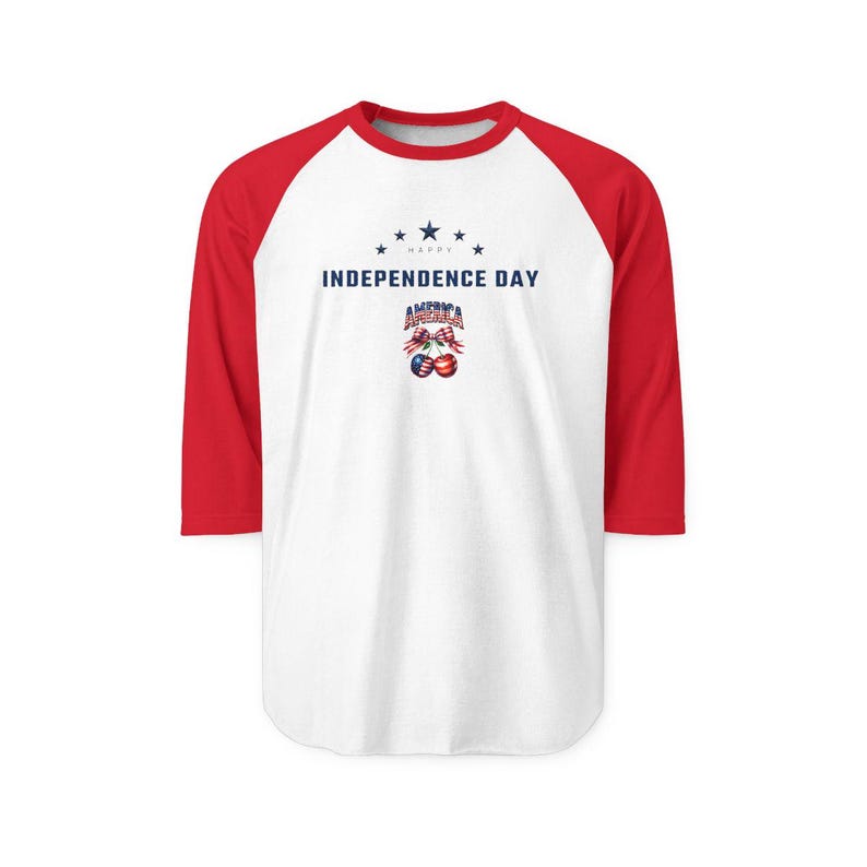 May include: A white baseball t-shirt with red three-quarter length sleeves. The front features the text HAPPY INDEPENDENCE DAY in blue, with a graphic of two cherries patterned with the American flag and a plaid bow above the word AMERICA.