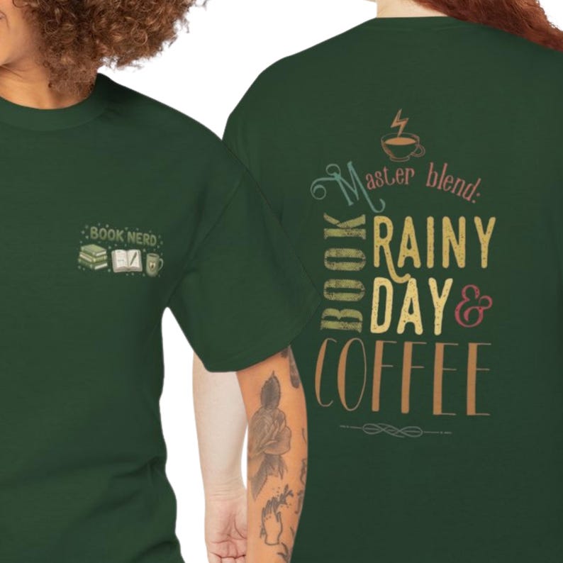 May include: A dark green t-shirt featuring a small graphic on the front left chest with a stack of books, an open book, and a coffee mug with the text "BOOK NERD". The back displays "Master blend: BOOK RAINY DAY & COFFEE" with a coffee cup icon.
