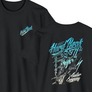 May include: A black t-shirt featuring a small blue Hard Rock logo on the front chest. The back displays a large graphic of a skeleton playing an electric guitar with the text Hard Rock 1971 Est. Original Guitar Company in blue and white.