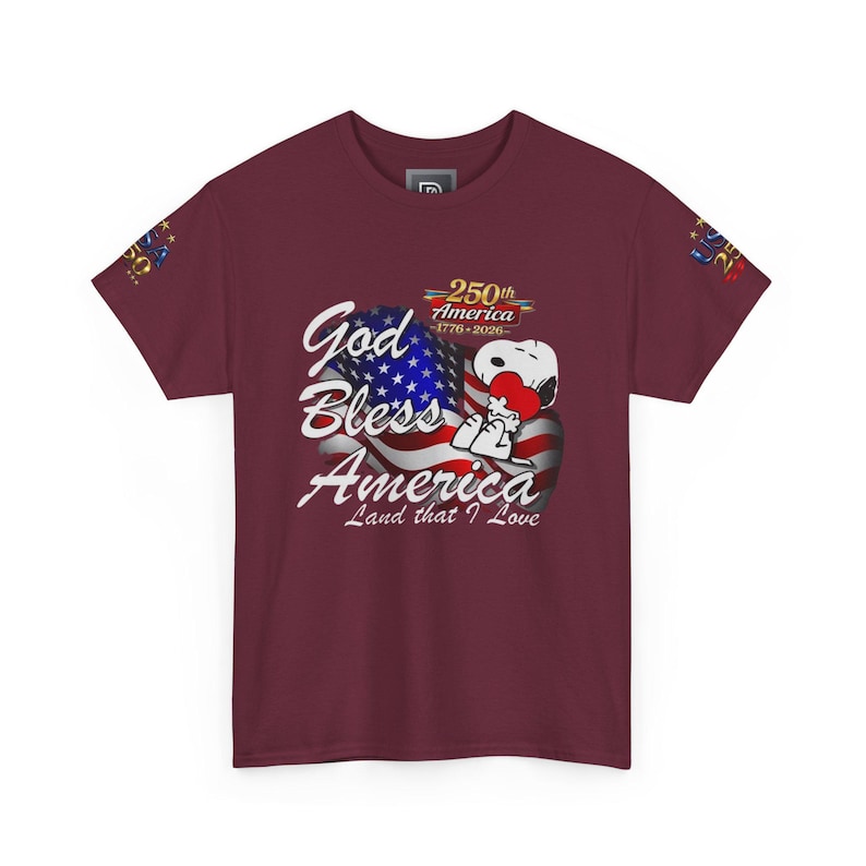 May include: Burgundy t-shirt featuring a graphic of Snoopy hugging a heart in front of an American flag. The text reads "God Bless America, Land that I Love" and "250th America 1776-2026".