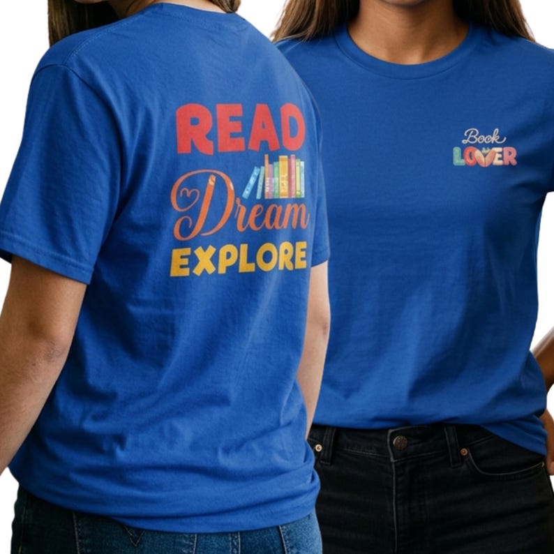 May include: A royal blue t-shirt featuring a graphic on the back with the text READ in red, Dream in orange script, and EXPLORE in yellow, accompanied by a row of colorful books. The front chest displays the text Book Lover in colorful letters.