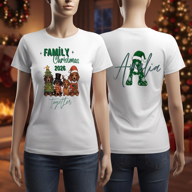 Puede incluir: Una camiseta blanca de manga corta con un gr&aacute;fico de cuatro perros salchicha con ropa festiva y el texto Family Christmas 2026 together. La parte trasera muestra una letra A grande en verde con copos de nieve blancos y un gorro de Pap&aacute; Noel.