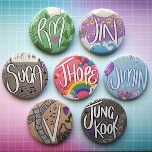 Pode incluir: Sete botões redondos com diferentes designs e cores. Cada botão apresenta um membro do grupo de K-pop BTS, com seu nome escrito em uma fonte estilizada. Os nomes são RM, Jin, Suga, J-Hope, Jimin, V e Jungkook.
