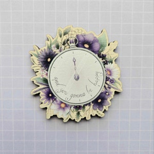 Op de afbeelding: Een houten klok met een bloemenontwerp en de tekst "and you gonna be happy".