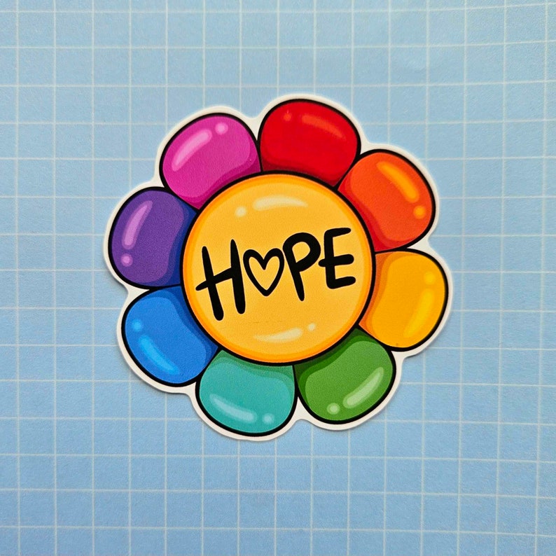 May include: A rainbow flower sticker with the word "HOPE" in the center. The flower has a yellow center and rainbow colored petals.