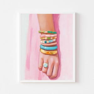 Könnte beinhalten: Eine Hand trägt einen Stapel bunter Armbänder, darunter türkisfarbene, rosafarbene und goldene. Die Hand trägt einen Ring mit einem großen türkisfarbenen Stein.