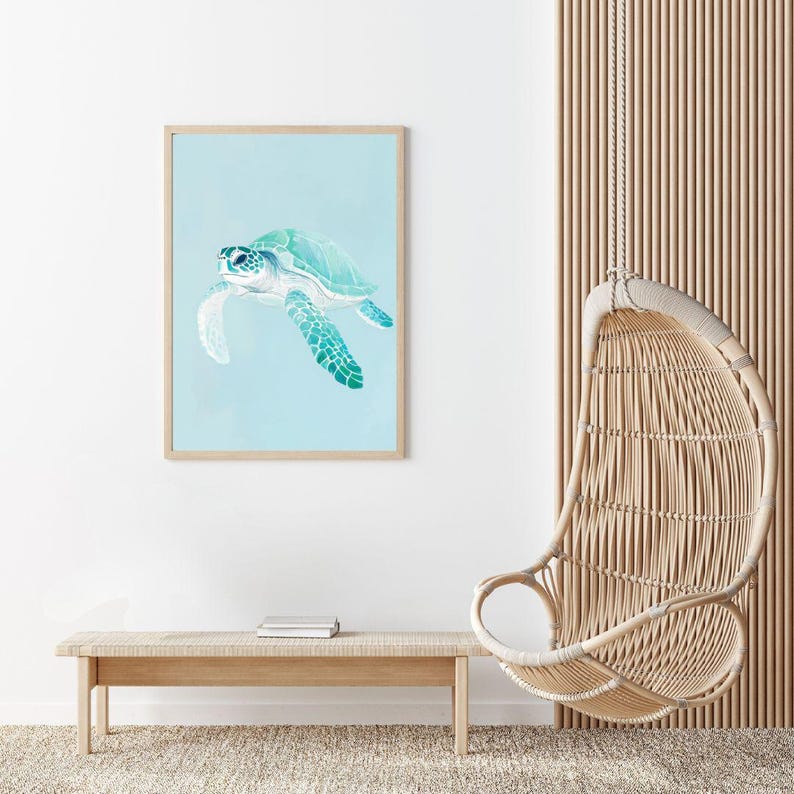 Puede incluir: Una impresi&oacute;n enmarcada de una pintura de acuarela de una tortuga marina nadando en un oc&eacute;ano azul claro. La tortuga es verde y azul con un caparaz&oacute;n blanco. La impresi&oacute;n est&aacute; colgada en una pared blanca en una habitaci&oacute;n con una silla colgante de mimbre y un banco de madera.
