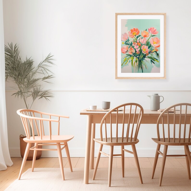Puede incluir: Una impresi&oacute;n enmarcada de una pintura que representa un ramo de flores rosas en un jarr&oacute;n sobre un fondo azul claro. La impresi&oacute;n est&aacute; colgada en una pared blanca sobre una mesa de comedor de madera con sillas.