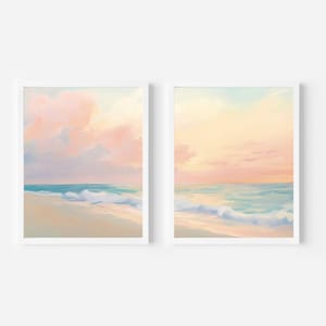 May include: Two framed beach landscape paintings. The artwork depicts a serene ocean scene with pastel colors. The sky is a blend of pink and yellow, with soft clouds. The ocean is a mix of turquoise and blue, with gentle waves.