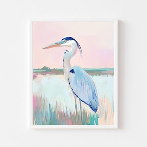 May include: A framed art print depicting a blue heron in a marsh setting. The artwork uses a soft, painterly technique with pastel shades of pink, blue, and green. The heron, with its detailed feathers and long beak, is the central subject.