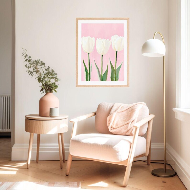 May include: A framed print of three white tulips on a pink background. The print is hanging on a white wall in a living room setting.