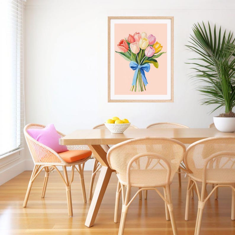 Pode incluir: Uma impress&atilde;o emoldurada de uma pintura em aquarela de um buqu&ecirc; de tulipas coloridas amarradas com uma fita azul sobre um fundo rosa claro.