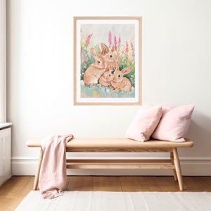 Peut inclure: Une impression encadr&eacute;e de trois lapins bruns assis dans un champ de fleurs roses et violettes. Les lapins regardent le spectateur.