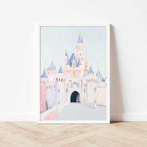 May include: A framed watercolor painting of a fairytale castle. The castle features pink, blue, and gold accents, with a light blue sky background. The artwork is displayed in a white frame.