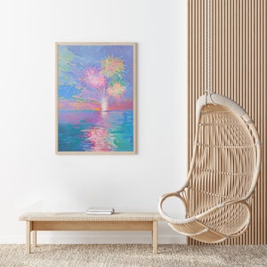 May include: A framed painting of a colorful fireworks display over a body of water. The painting is in a light wood frame and is hanging on a white wall. A wicker hanging chair and a wooden bench are in the foreground.