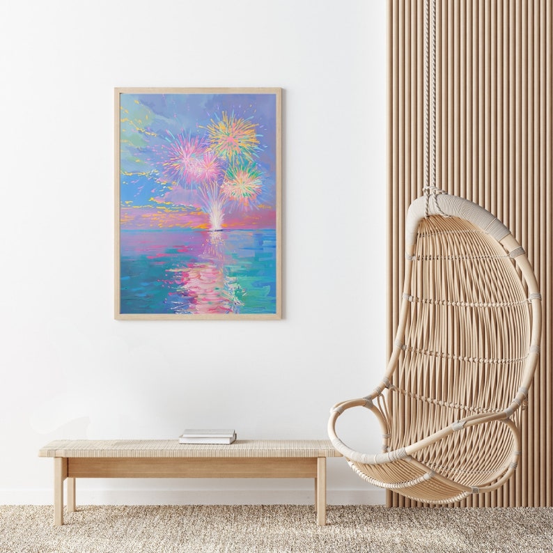 May include: A framed painting of a colorful fireworks display over a body of water. The painting is in a light wood frame and is hanging on a white wall. A wicker hanging chair and a wooden bench are in the foreground.