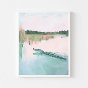K&ouml;nnte beinhalten: Ein Kunstdruck eines Alligators, der in einem See schwimmt. Das Kunstwerk verwendet eine Pastellfarbpalette mit Rosa-, Gr&uuml;n- und Blaut&ouml;nen. Der Alligator ist gr&uuml;n und das Wasser hellblau.