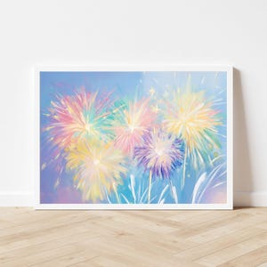 May include: A framed art print featuring a colorful fireworks display. The artwork showcases vibrant bursts of yellow, pink, purple, and green against a light blue background. The painting is in a white frame, suitable for home decor.