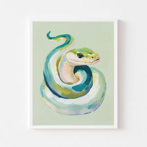 以下が含まれることがあります： フレームに入った、丸まったヘビの絵。ヘビは青、緑、黄色、白の色合いで描かれています。このアートワークは、淡い緑色の背景に対して、柔らかく絵画的なスタイルです。