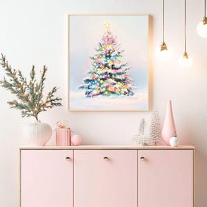 Puede incluir: Un cuadro enmarcado de un &aacute;rbol de Navidad con luces de colores y una estrella dorada. El cuadro est&aacute; colgado sobre un mueble rosa con objetos decorativos, como un jarr&oacute;n, una caja de regalo y adornos. La escena evoca un ambiente festivo navide&ntilde;o.