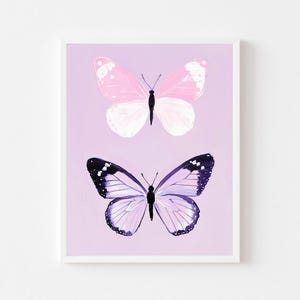 Puede incluir: Dos mariposas sobre un fondo morado claro. Una mariposa es rosa y blanca, la otra es morada y negra.