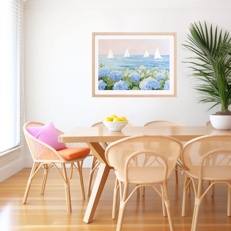 Pu&ograve; includere: Un dipinto ad acquerello incorniciato raffigura barche a vela su un mare blu, con ortensie blu in primo piano. Il dipinto &egrave; appeso sopra un tavolo da pranzo in legno con sedie intrecciate. Un cuscino rosa e un cuscino arancione aggiungono colore.