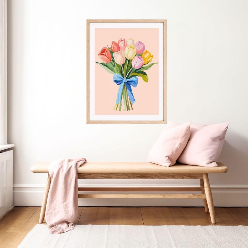 Pode incluir: Uma impress&atilde;o emoldurada de um buqu&ecirc; de tulipas coloridas amarradas com uma fita azul sobre um fundo rosa claro.