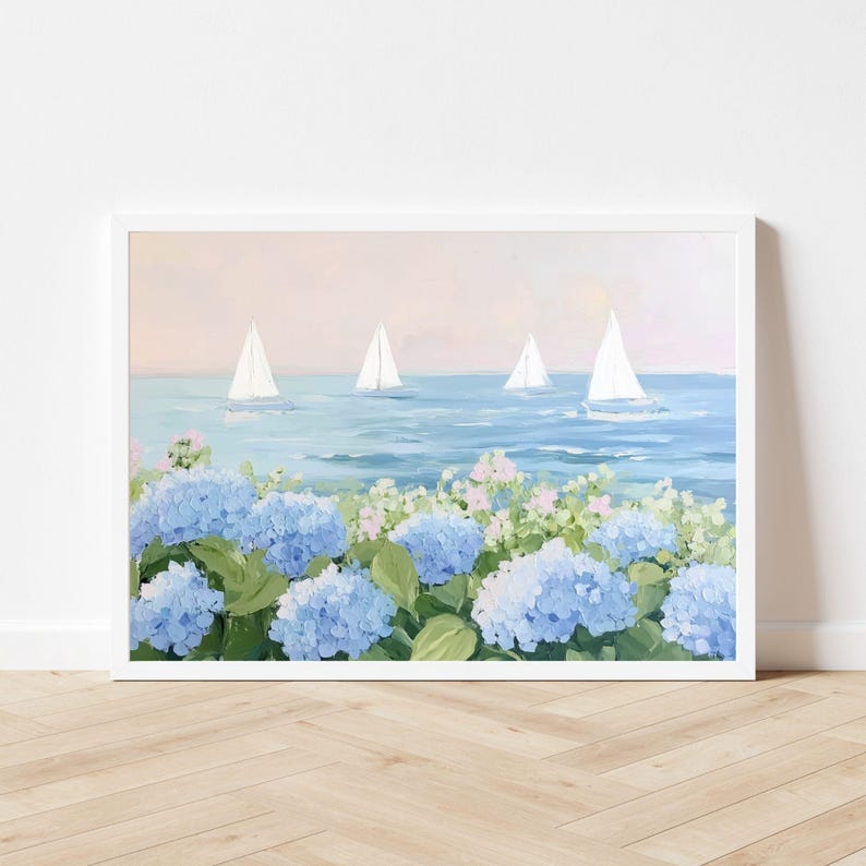 Pu&ograve; includere: Dipinto incorniciato raffigurante una scena costiera con barche a vela su un mare blu sotto un cielo rosa e blu. Il primo piano presenta vibranti fiori di ortensia blu e fogliame verde, creando un paesaggio sereno.