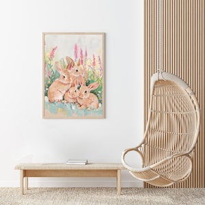 Peut inclure: Une peinture de trois lapins bruns assis dans un champ de fleurs roses et violettes. Les lapins regardent le spectateur.