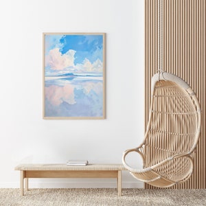 May include: A framed painting of a blue sky with white clouds reflected in a body of water. The painting is hanging on a white wall next to a light wood bench and a hanging wicker chair.