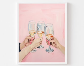 May include: An art print of three champagne flutes clinking together, filled with a golden liquid. The hands holding the glasses have pink nail polish, set against a pink background. The print is framed in a white border.