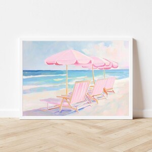 May include: A painting of a beach scene with three pink lounge chairs under pink umbrellas. The chairs are facing the ocean, which is painted in shades of blue and green. The sand is white and the sky is a light blue with white clouds.