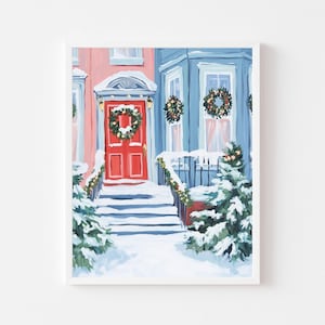 以下が含まれることがあります： 雪に覆われた家の外観を描いた額入りの絵画。赤い玄関ドアにはリースが飾られ、青い家には窓にリースが飾られています。雪が階段と常緑樹を覆い、お祝いの冬のシーンを作り出しています。