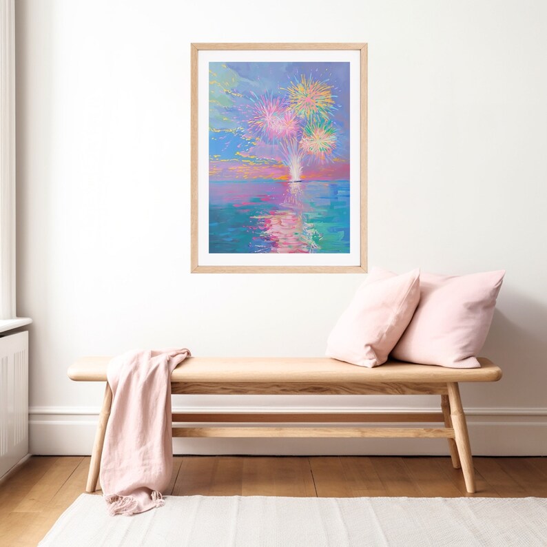 May include: A framed painting of a colorful fireworks display over a body of water. The fireworks are pink, yellow, and green, and they are reflected in the water. The sky is a light blue color, and the water is a turquoise color.