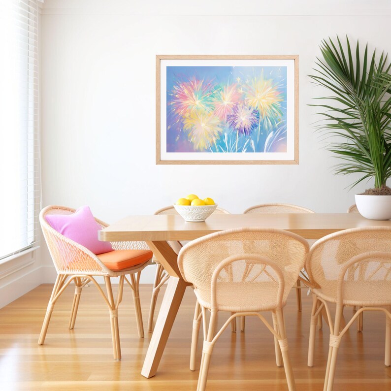 May include: A dining room scene featuring a wooden table and woven chairs. A framed artwork of colorful fireworks hangs on the white wall. A pink pillow and orange cushion add pops of color. A potted plant and a bowl of lemons complete the decor.