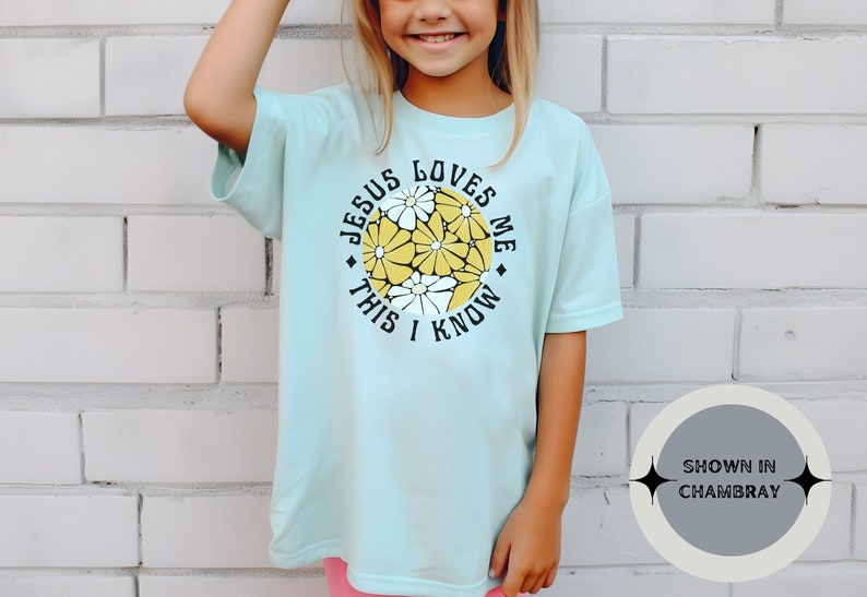 May include: A light blue t-shirt with a white daisy print and the text "Jesus Loves Me This I Know".