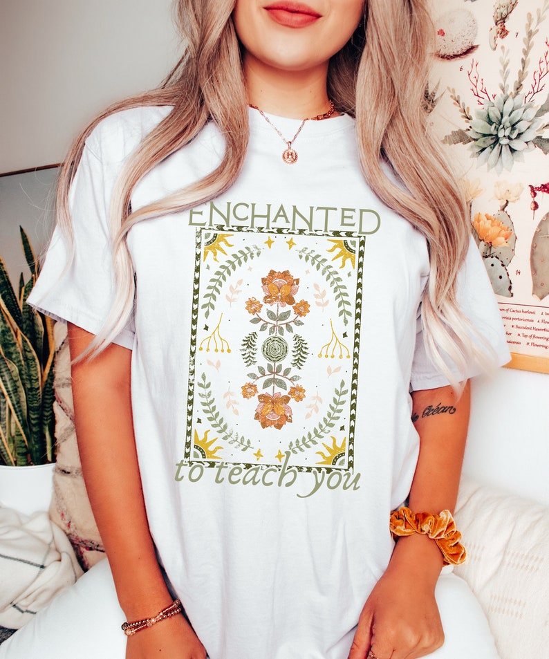 May include: White t-shirt with a floral design and the text "ENCHANTED to teach you".
